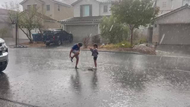 Las Vegas Review Journal News | Children splash in the water during a rainstorm near the M Casino